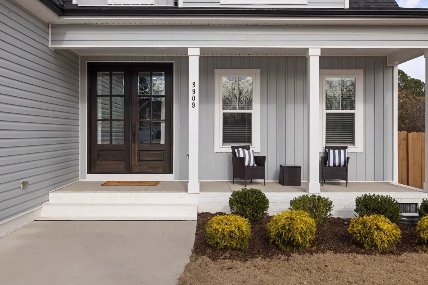 Modern front porch with dark wood door and gray siding